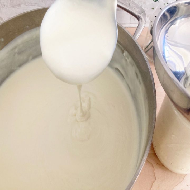 Thickened white sauce pouring from ladel.