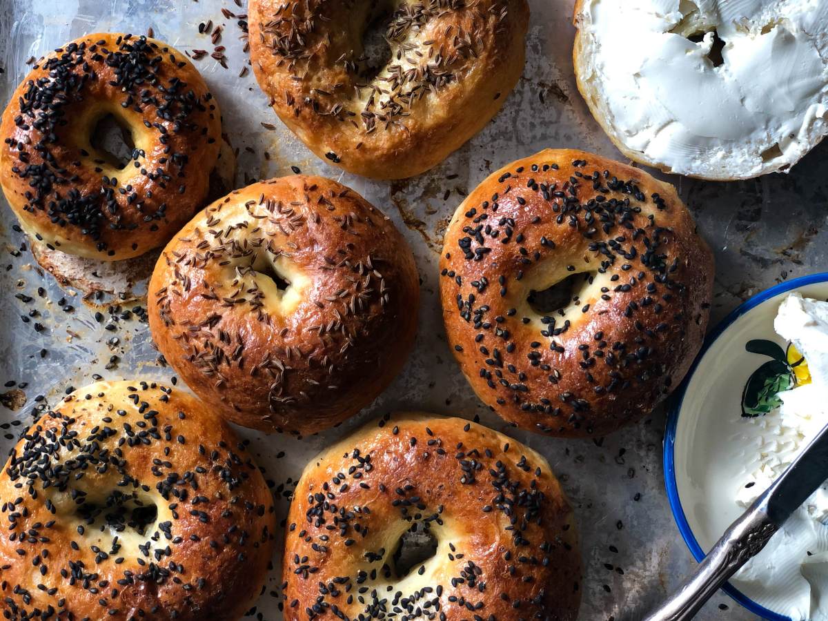 Bagels with black sesame seeds, herbs, and caraway seeds with cream cheese on the side.