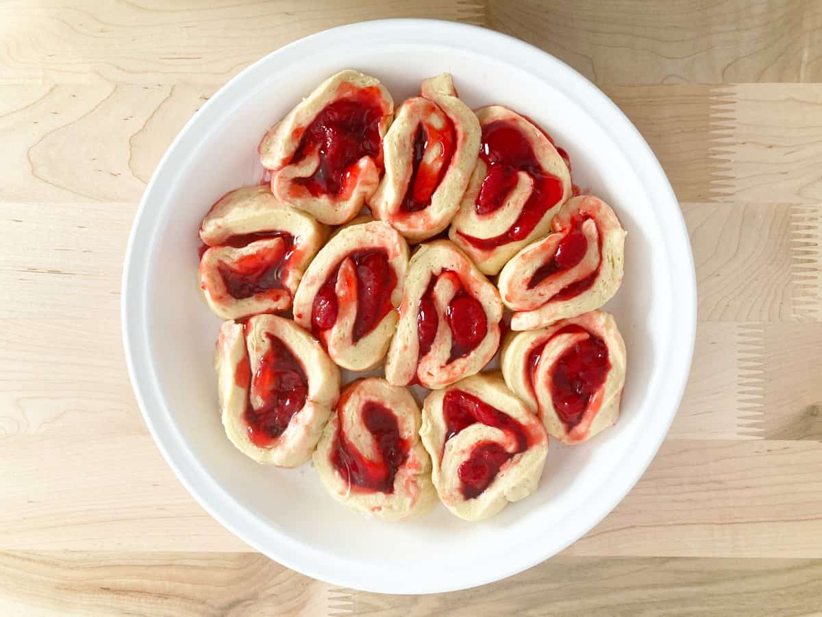 Uncooked strawberry rolls in white pie pan.