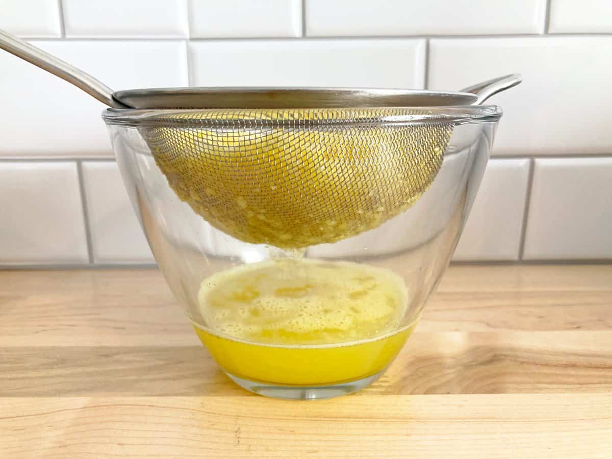 Side view of pineapple juice dripping into the bowl from the sieve or strainer.