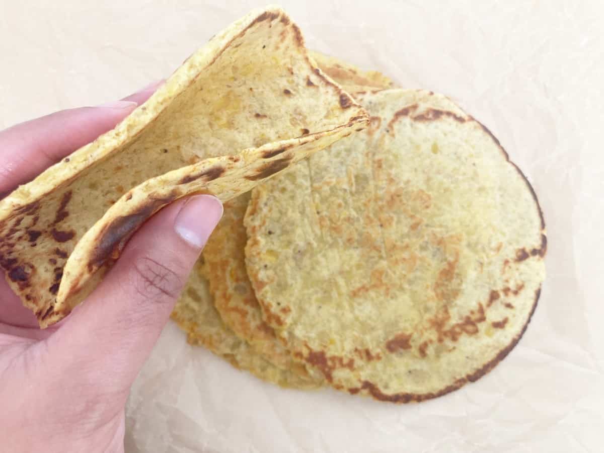 Hand holding plantain tortilla forming into a street taco. Showing its soft and pliable.
