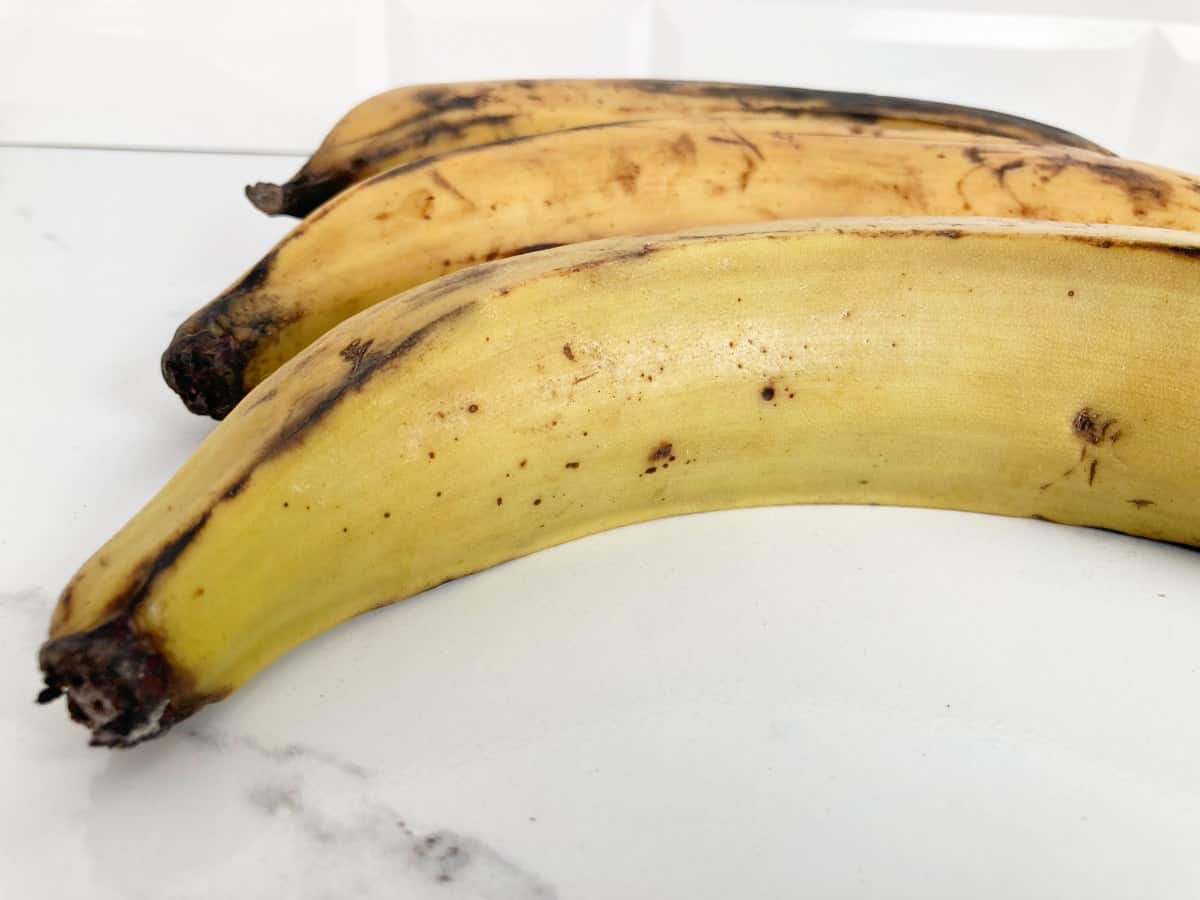 Three fresh plantains showing one that is slightly green.