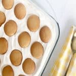 Easy banana-less pudding with whipped topping. Next to a gold serving spoon, yellow and white checkered kitchen towel.