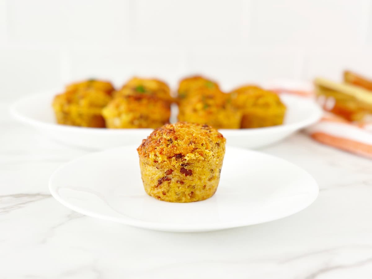 Single cornbread stuffing muffin on white plate.