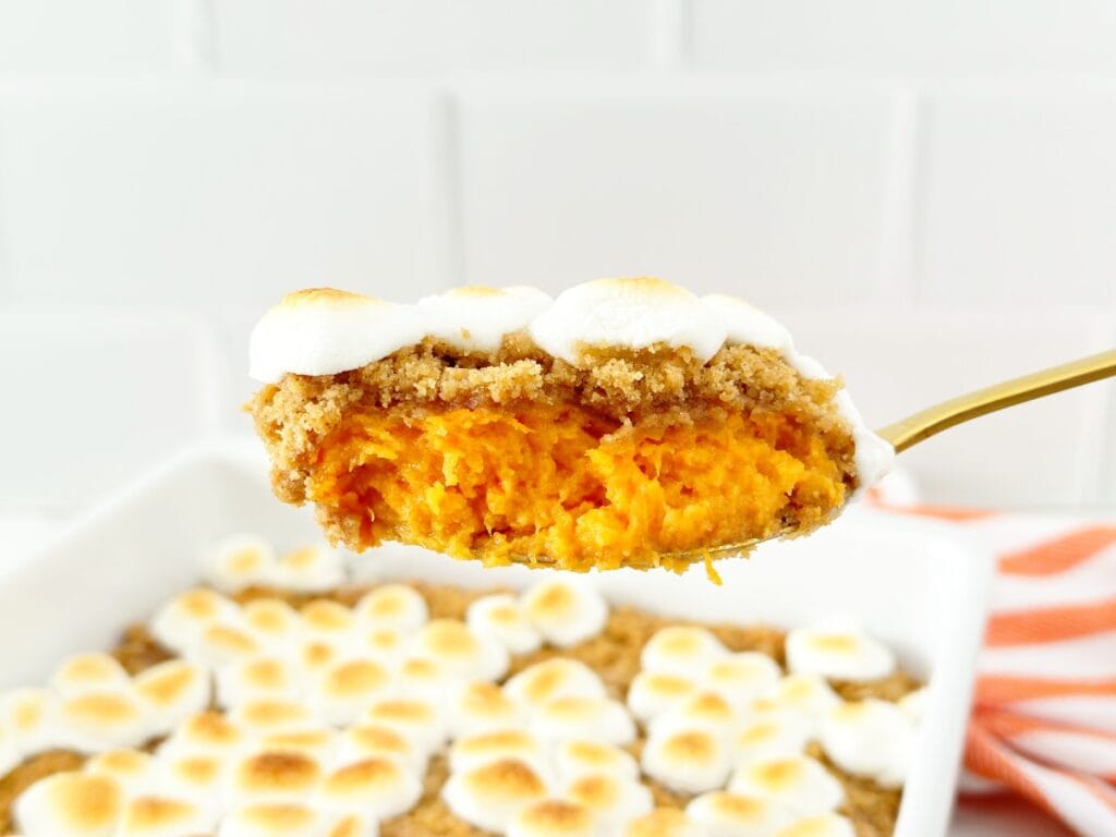 Gold serving spoon holding sweet potato crumble casserole.