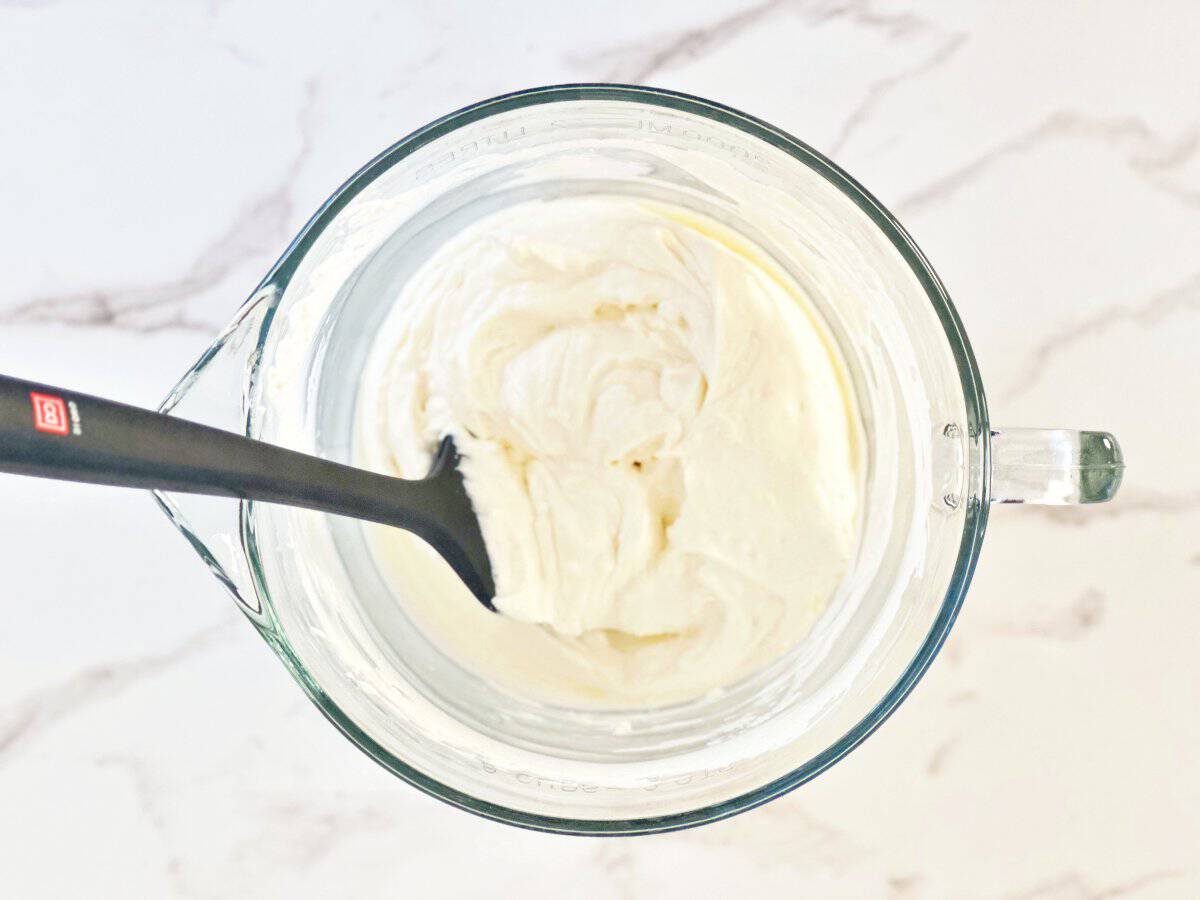 Down view of clear mixing bowl with cream cheese mixture.