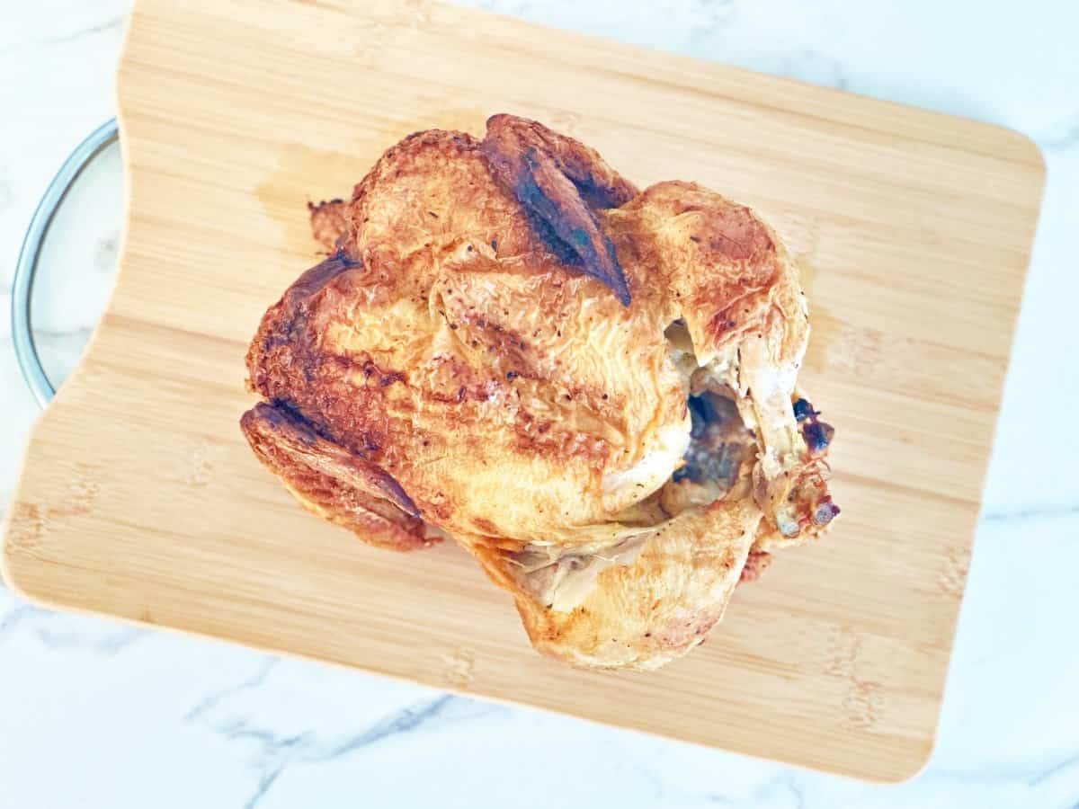 Store bought rotisserie chicken on wood cutting board.