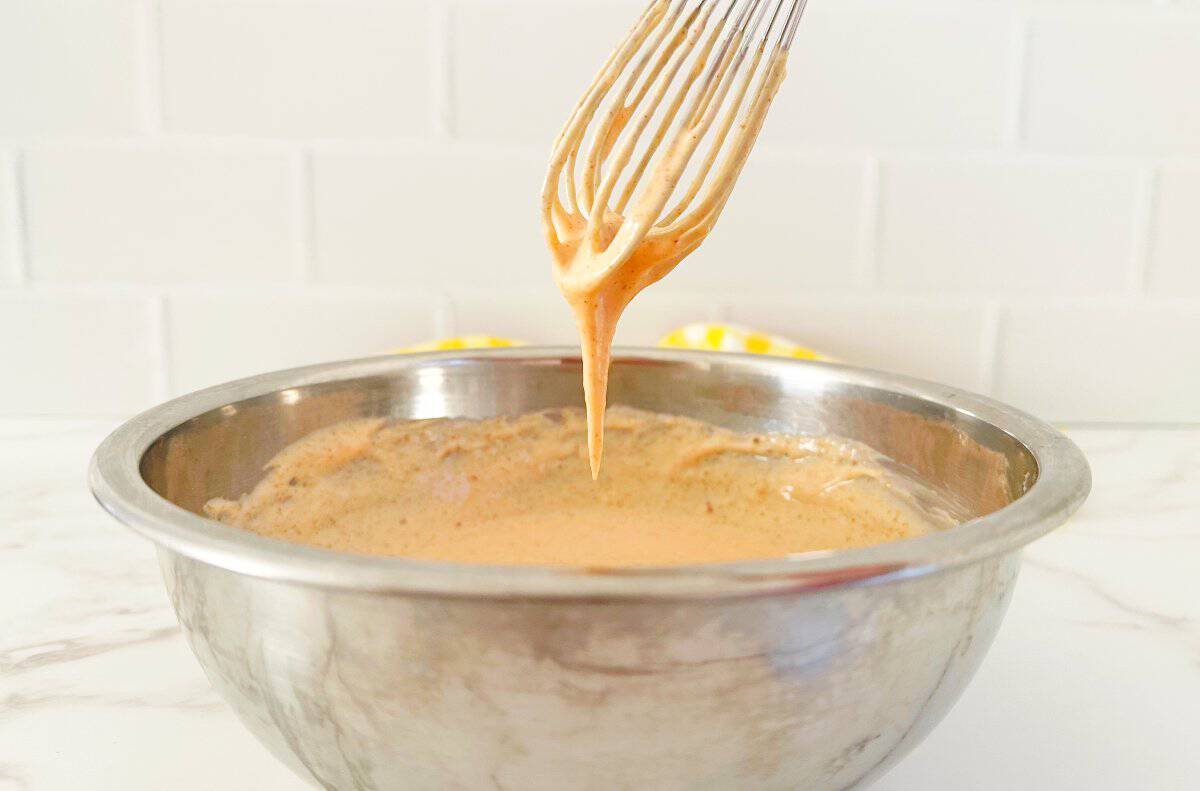 Whisk dripping thick yum yum sauce into silver mixing bowl.