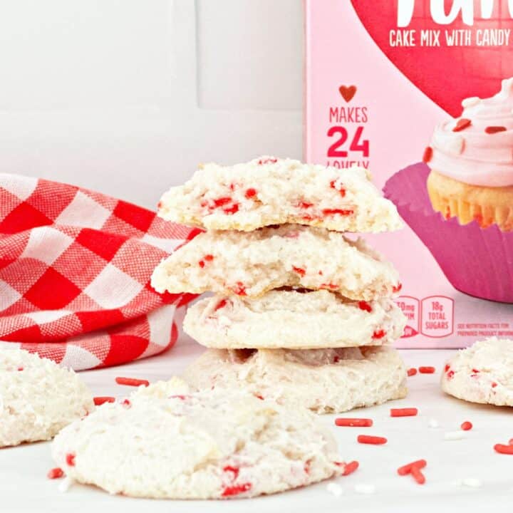 Stack of Valentine's Day cake mix cookies and the top cookie is in half to show chewy texture.