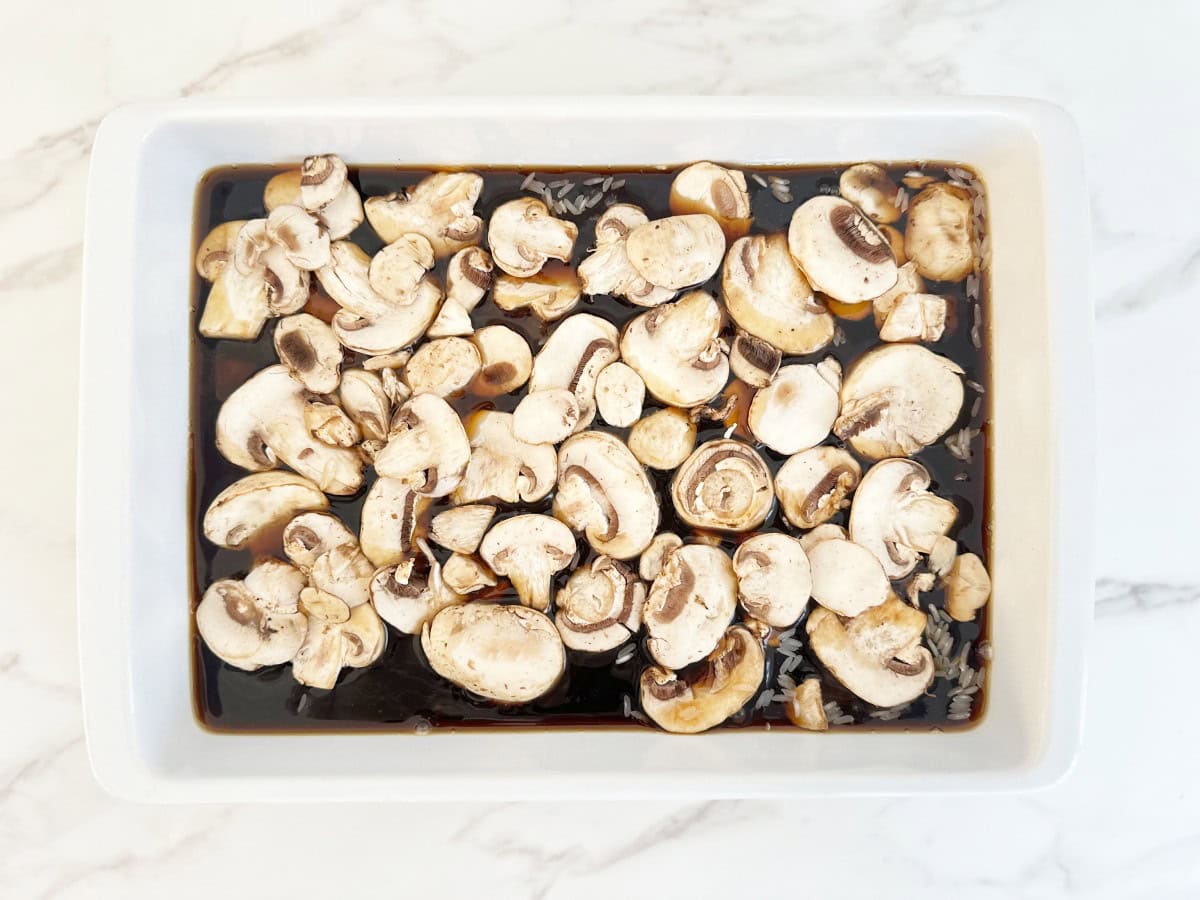 Down view white baking dish with sliced beef consommé and mushrooms.