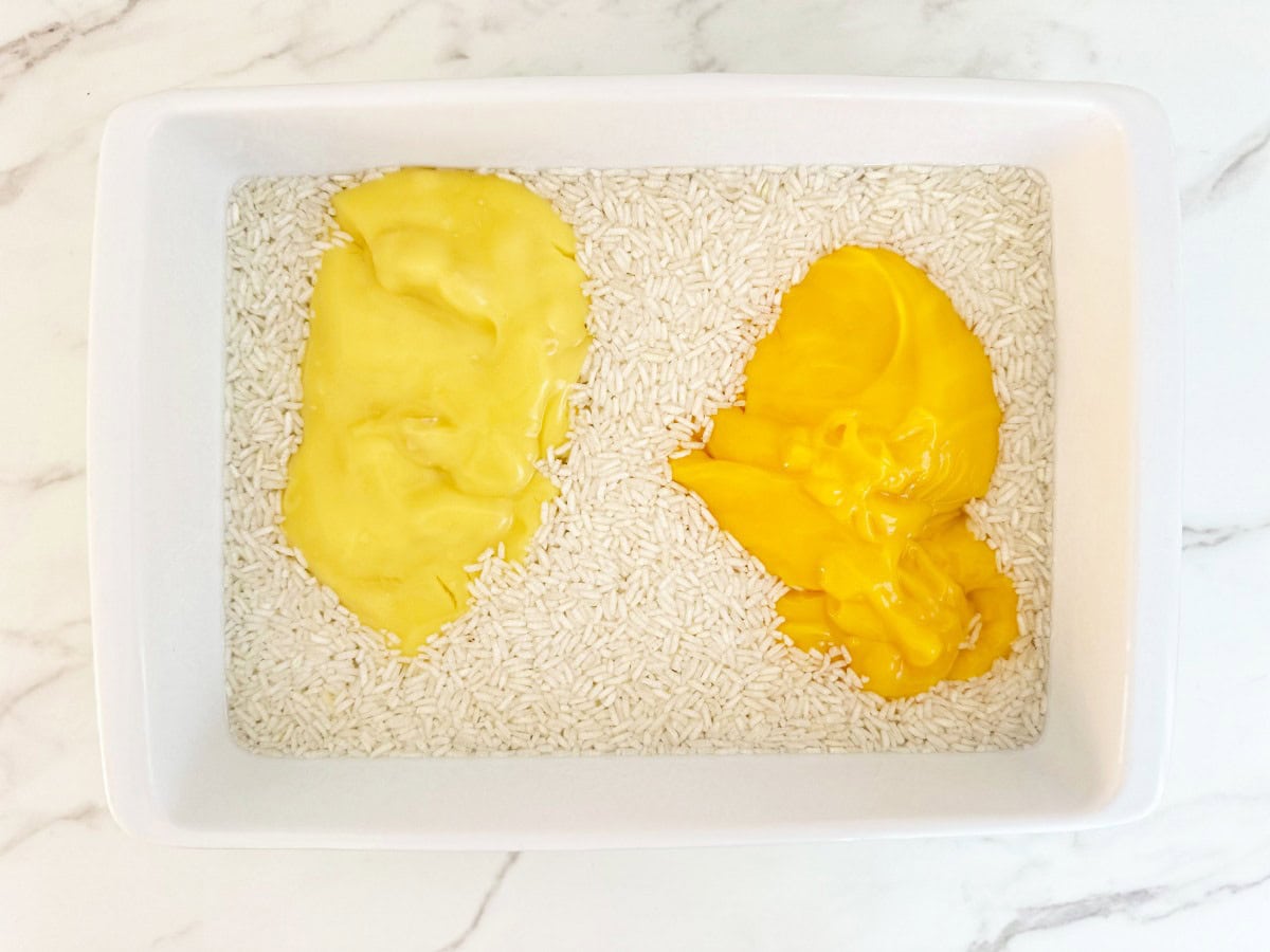 Down view white baking dish with unmixed condensed soup, rice, and broth.