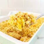 Serving spoon holding a portion cheesy chicken and rice casserole with ritz crackers.