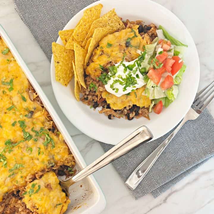 Down view of chicken taco rice casserole with queso in baking dish. Next to a chicken rice bowl and fork.