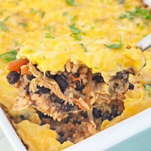 Serving spoon holding chicken taco rice casserole with queso.
