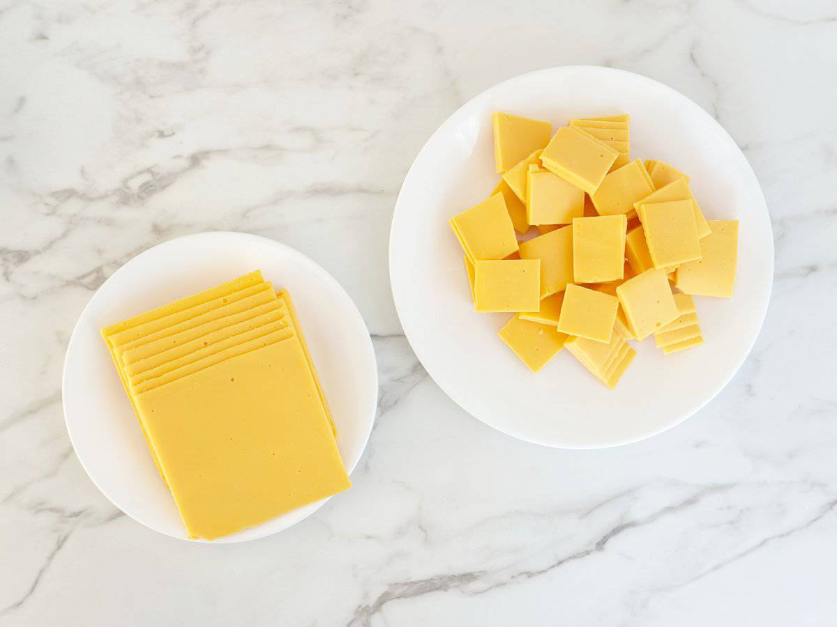 White plates with cubed and sliced American deli cheese.