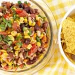 Down view bowl with cowboy caviar. Next to yellow corn tortilla chips.
