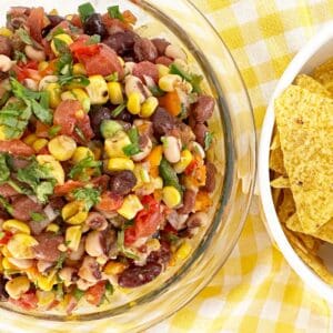 Down view bowl with cowboy caviar. Next to yellow corn tortilla chips.