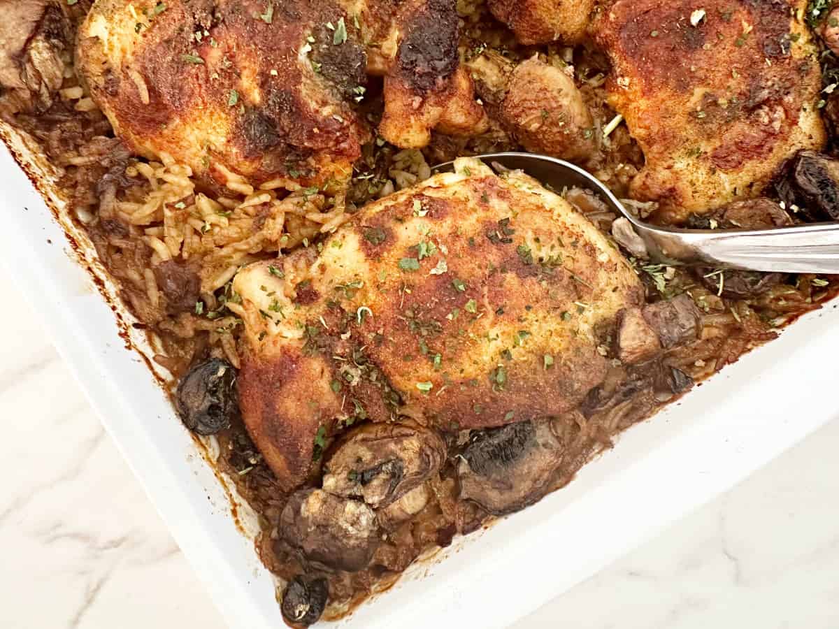 Down view of a silver serving spoon scooping out a portion of stick of butter rice with chicken.
