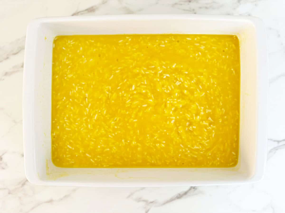 Down view white baking dish with mixed condensed soup, rice, and broth.