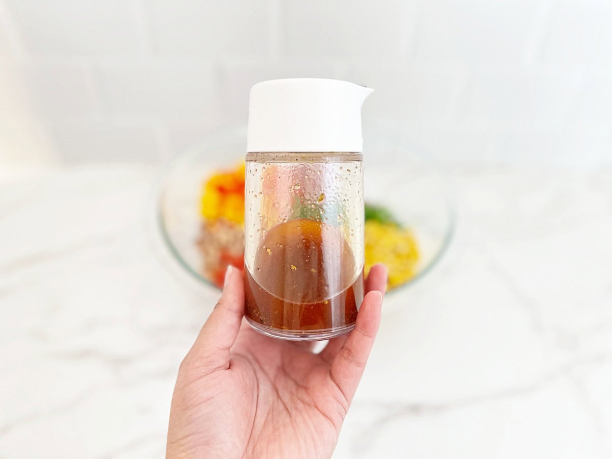 Hand holding dressing bottle with taco vinaigrette.