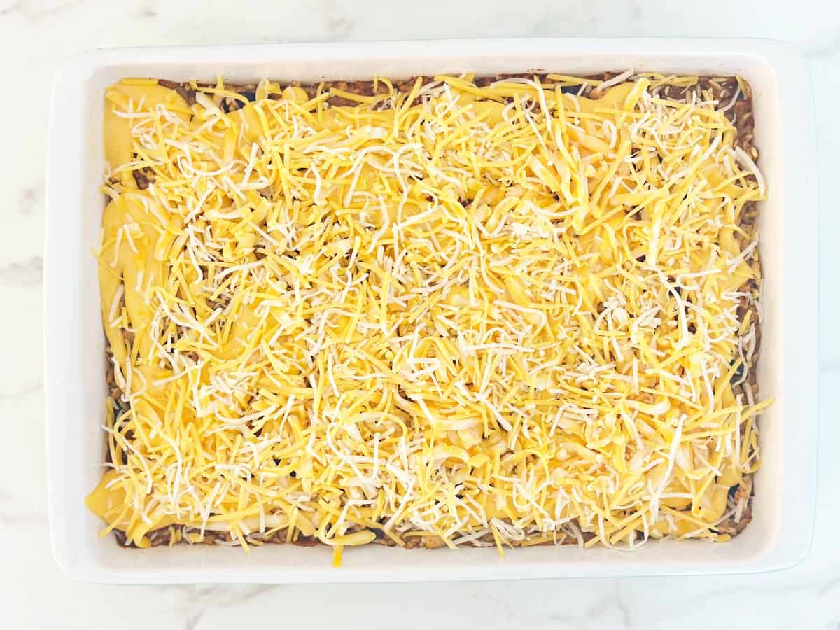 Down view white baking dish with shredded cheese and queso.