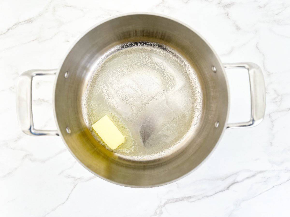 Down view of half stick of butter in silver pot.