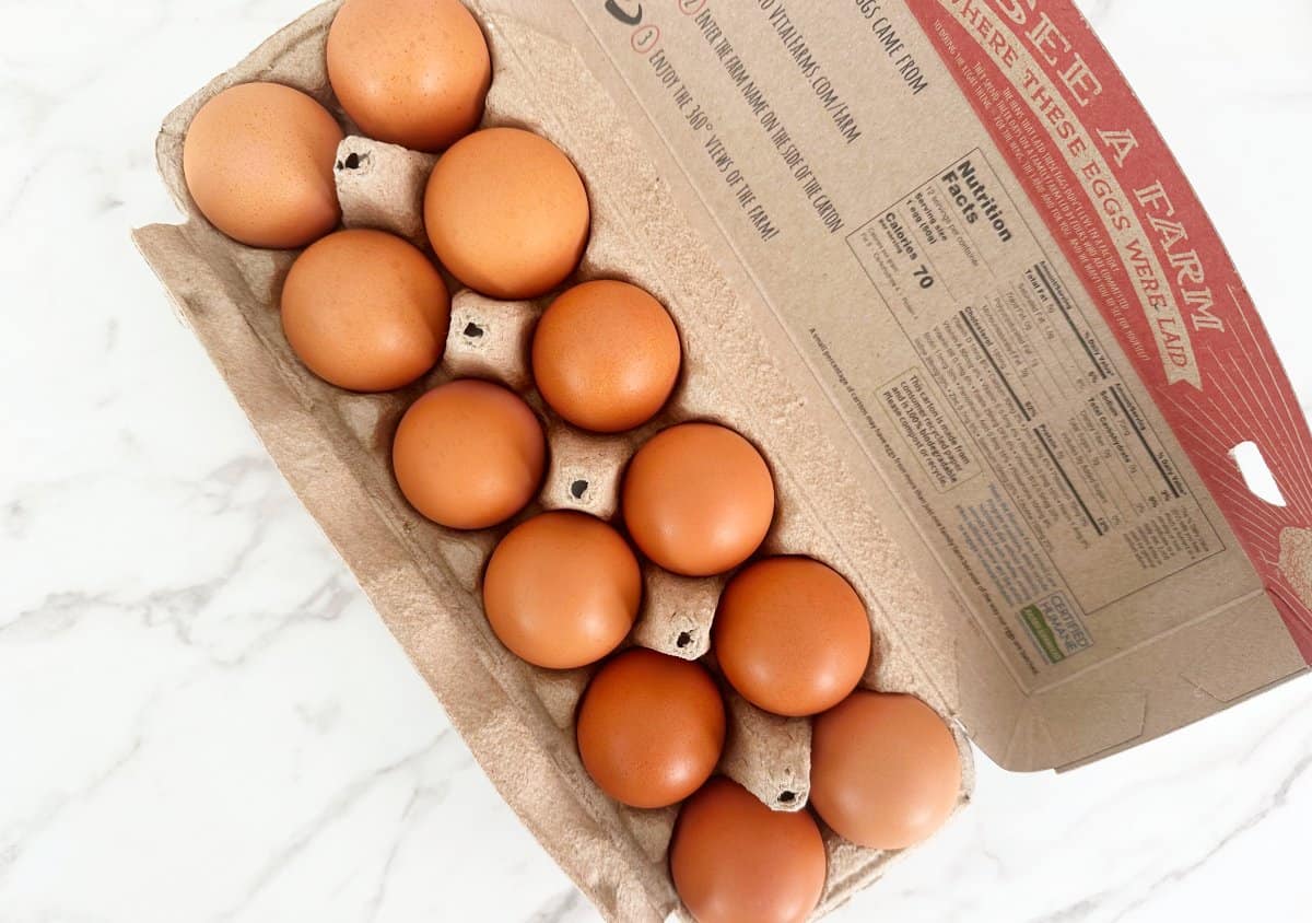 Down view of a dozen brown eggs in a carton.