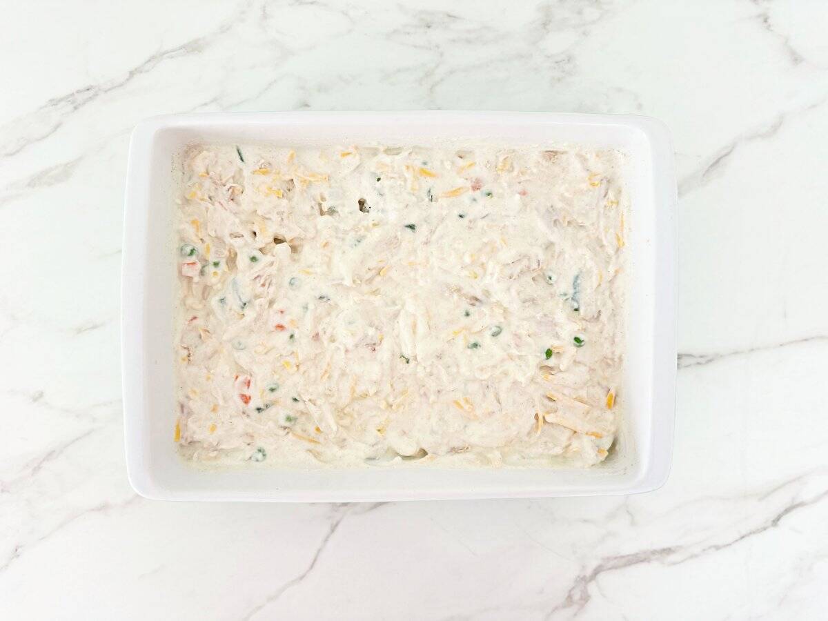 Down view of white baking dish with unbaked chicken pot pie mixture.