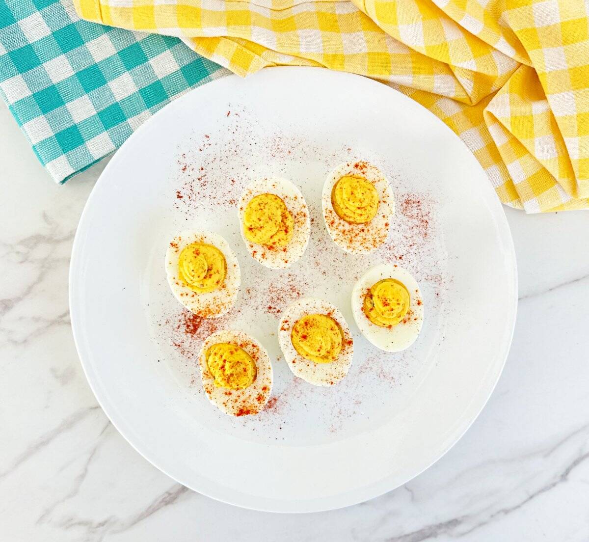 Down view of a white plate with classic southern deviled eggs. Sprinkled with paprika.