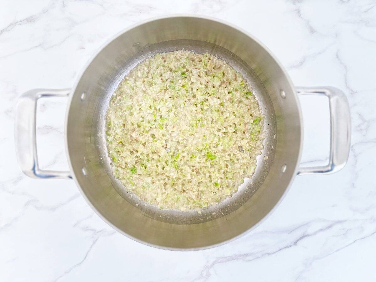 Down view of butter and vegetables in silver pot.