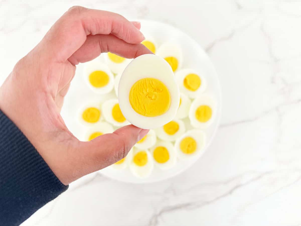Hand holding a hard boiled egg cut in half.