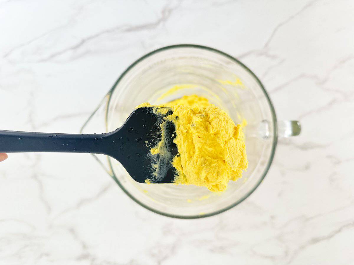 Down view of a black rubber spatula with deviled egg yolk mixture