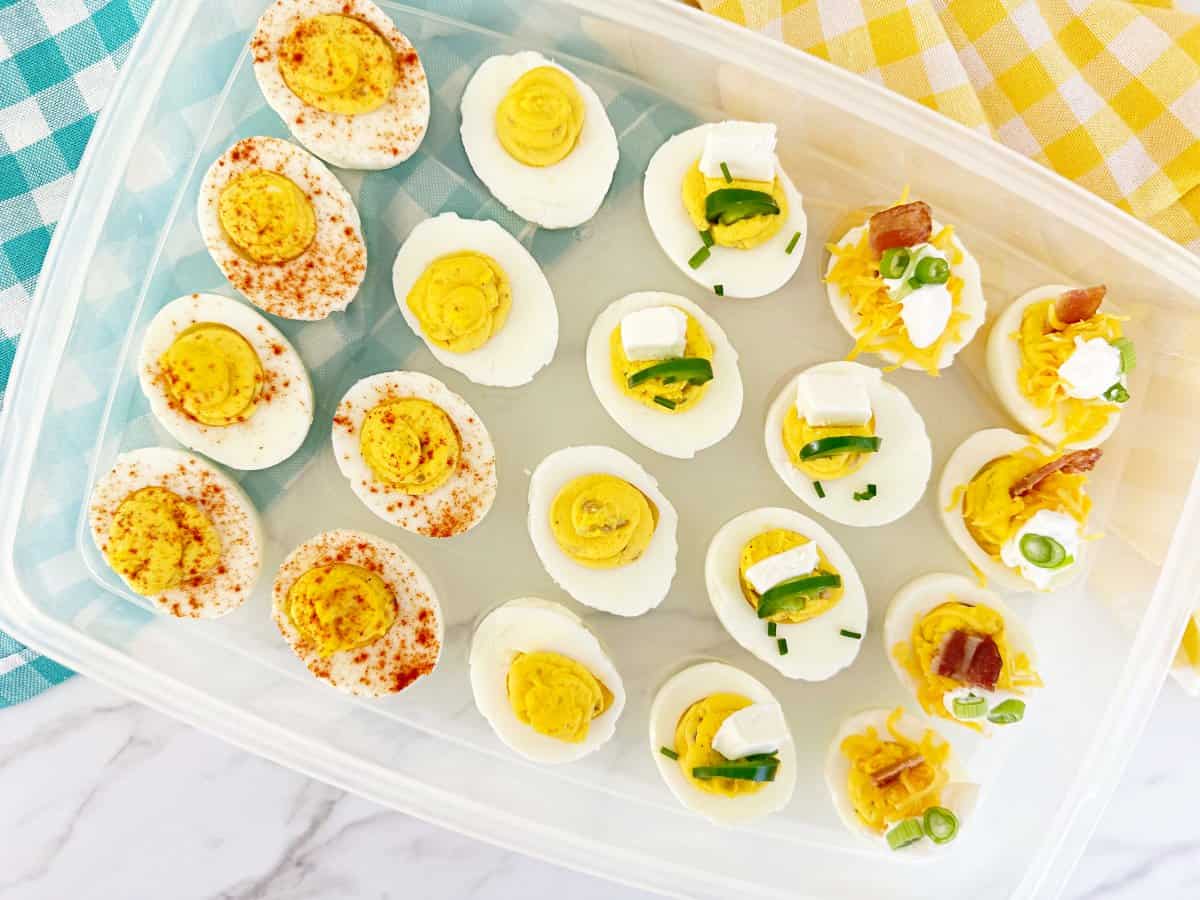 Down view of deviled eggs with toppings in plastic deviled egg container.