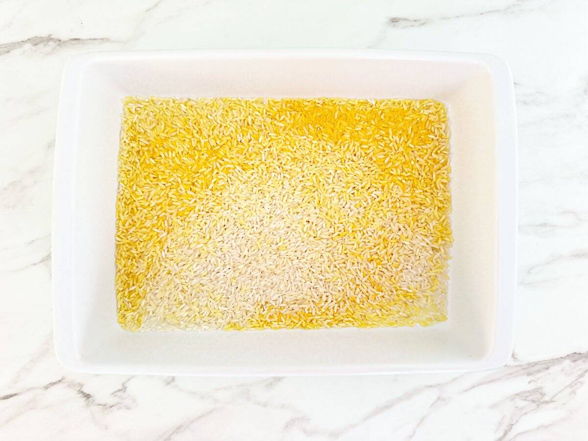 Down view of white baking dish with yellow rice mix.