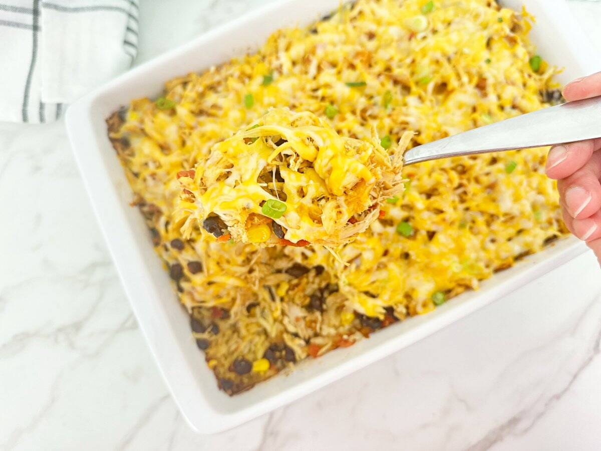 Down view cheesy Mexican chicken rice casserole on silver serving spoon.