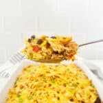 Serving spoon holding a portion of Mexican chicken rice casserole with yellow rice.