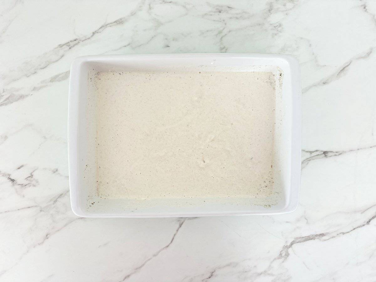 Down view white baking dish with mixed wet ingredients.