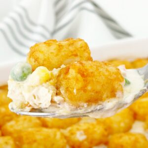 Close up view of a serving spoon with tater tot chicken pot pie casserole.
