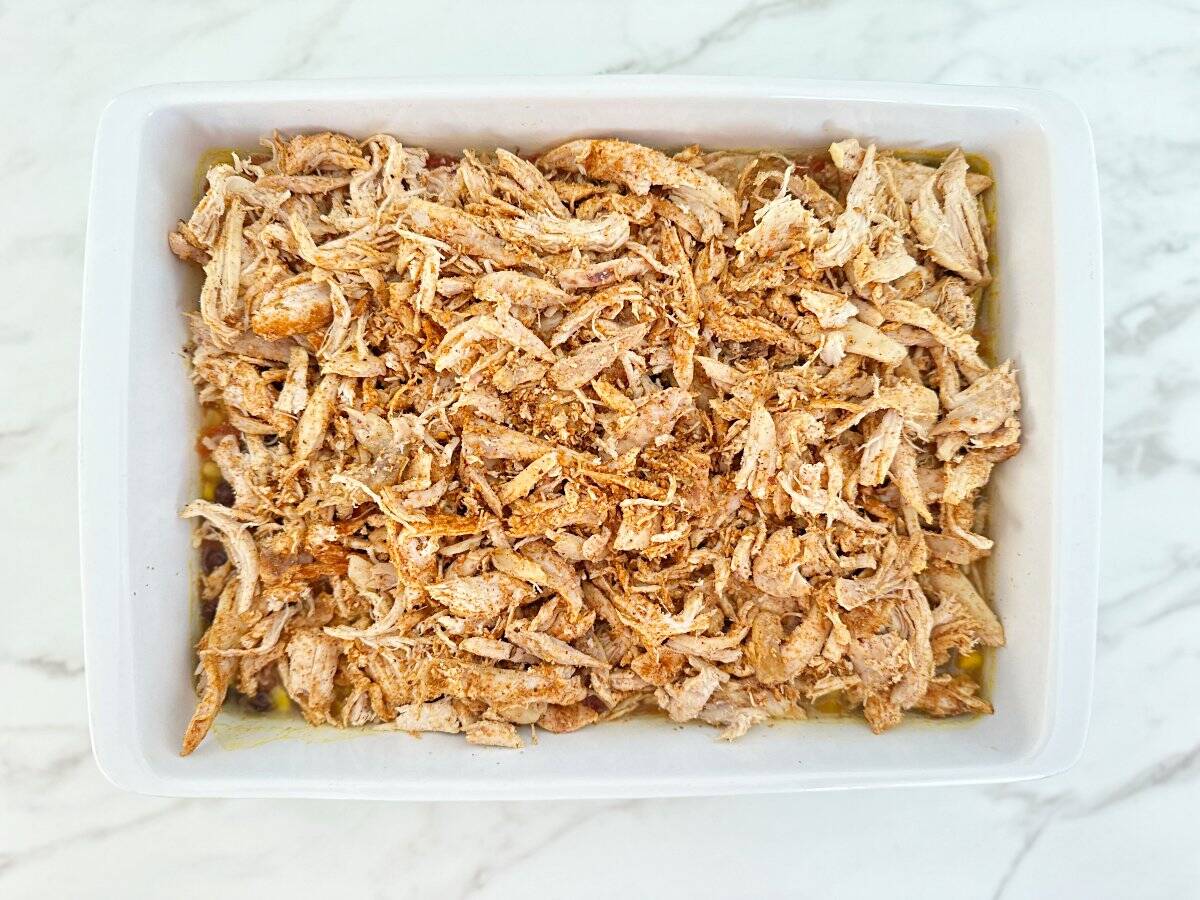 Down view white baking dish with taco seasoned rotisserie chicken.