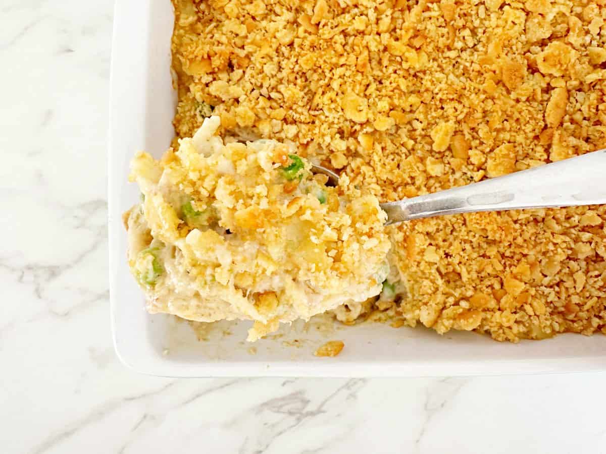 Down view tuna noodle casserole with ritz cracker topping on silver serving spoon.