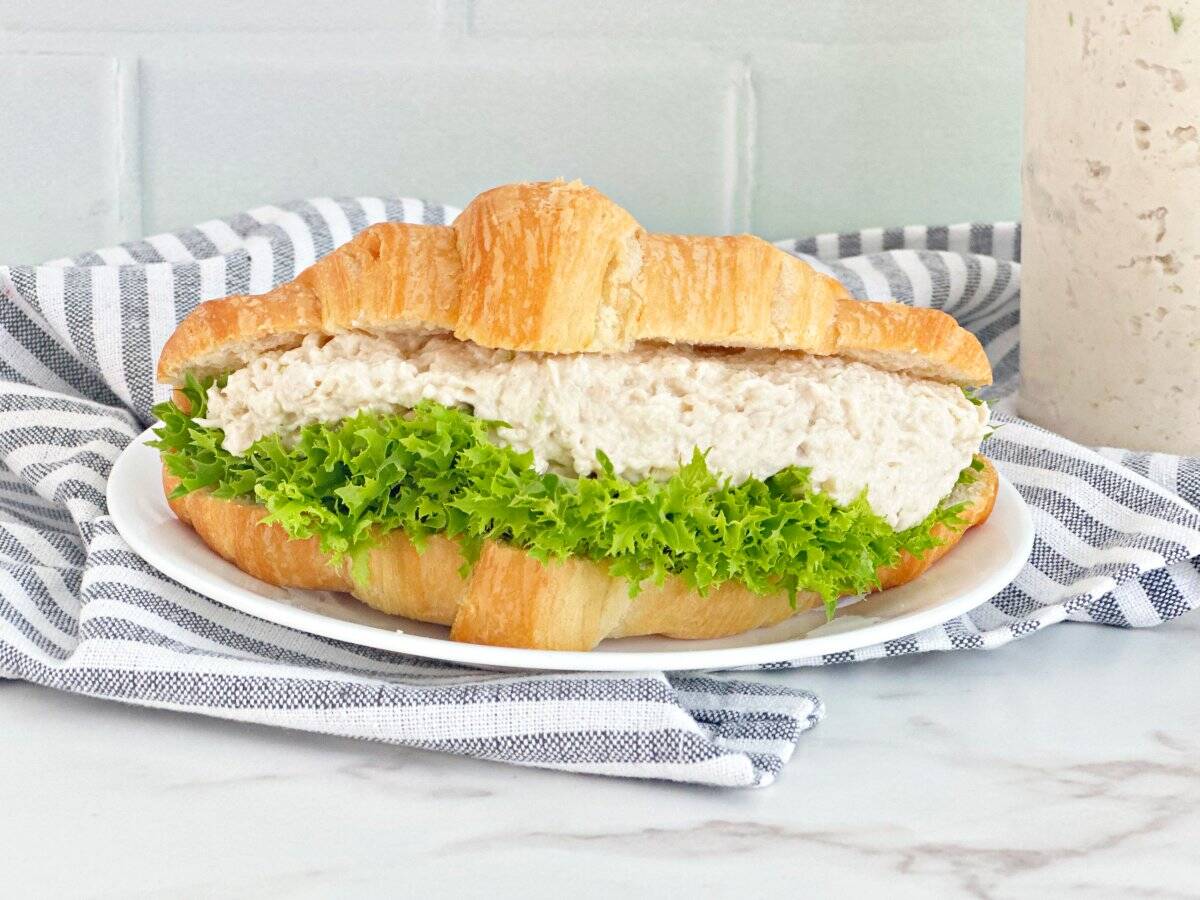 Close up view of chicken salad croissant sandwich with lettuce.