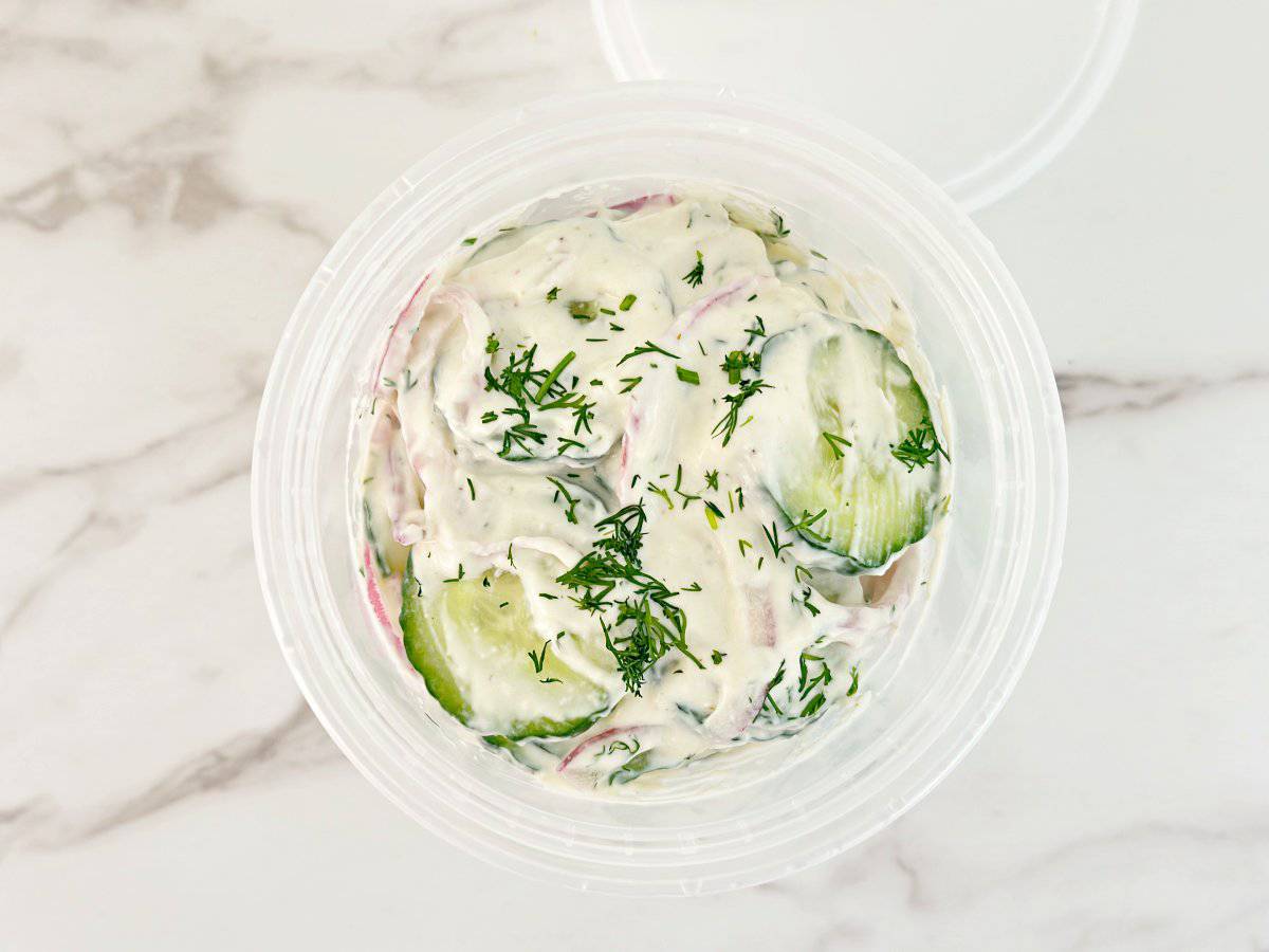 Down view of deli container with creamy cucumber salad.