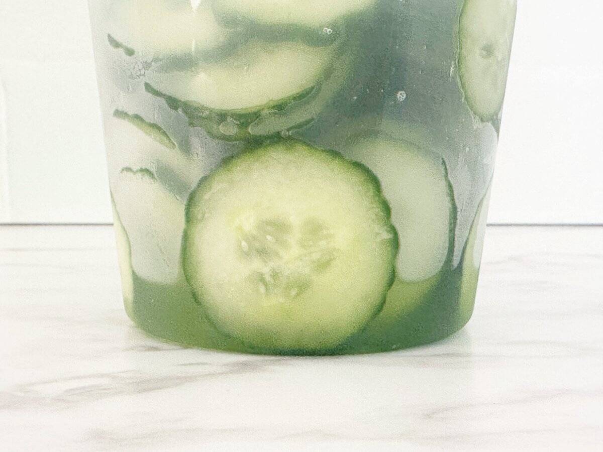 Side view of salted cucumber salad liquid at the bottom of the deli container.