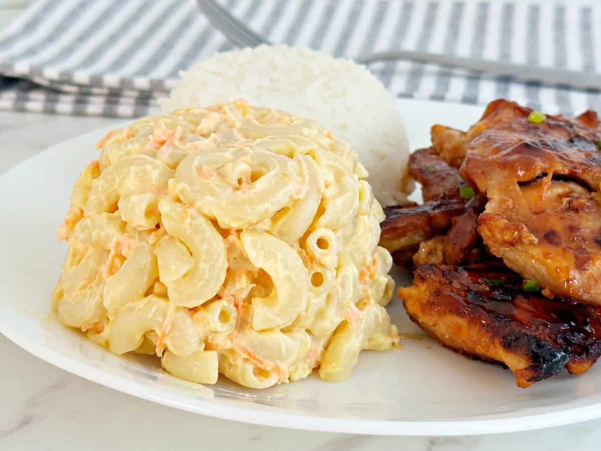 Side view of easy Hawaiian macaroni salad on plate with huli huli chicken and white rice.