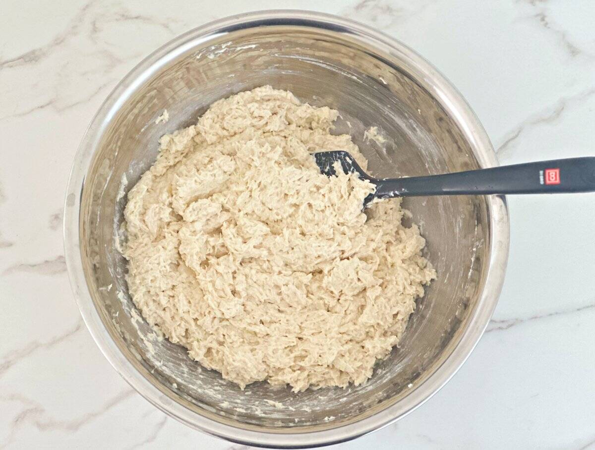 Down view of chicken salad in silver mixing bowl.