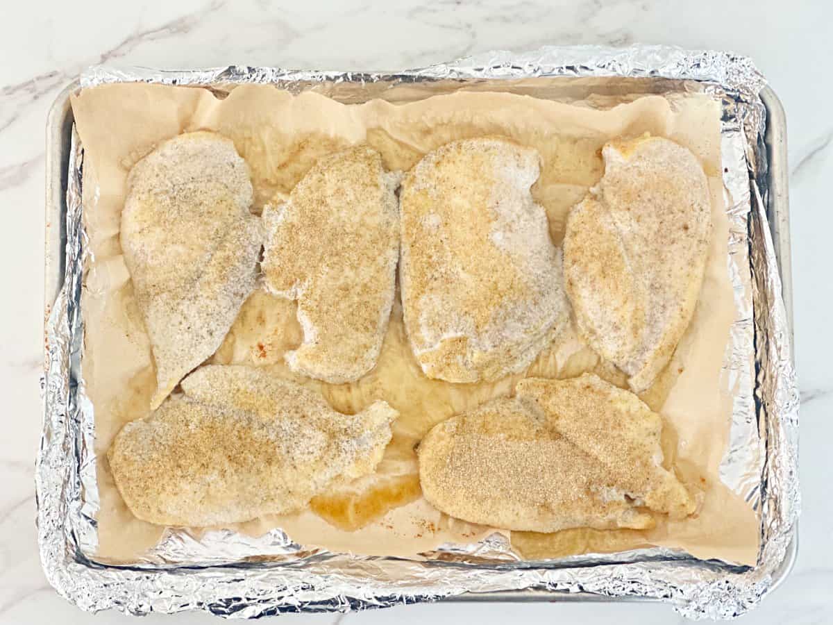 Down view of cooked seasoned chicken breasts on sheet pan.