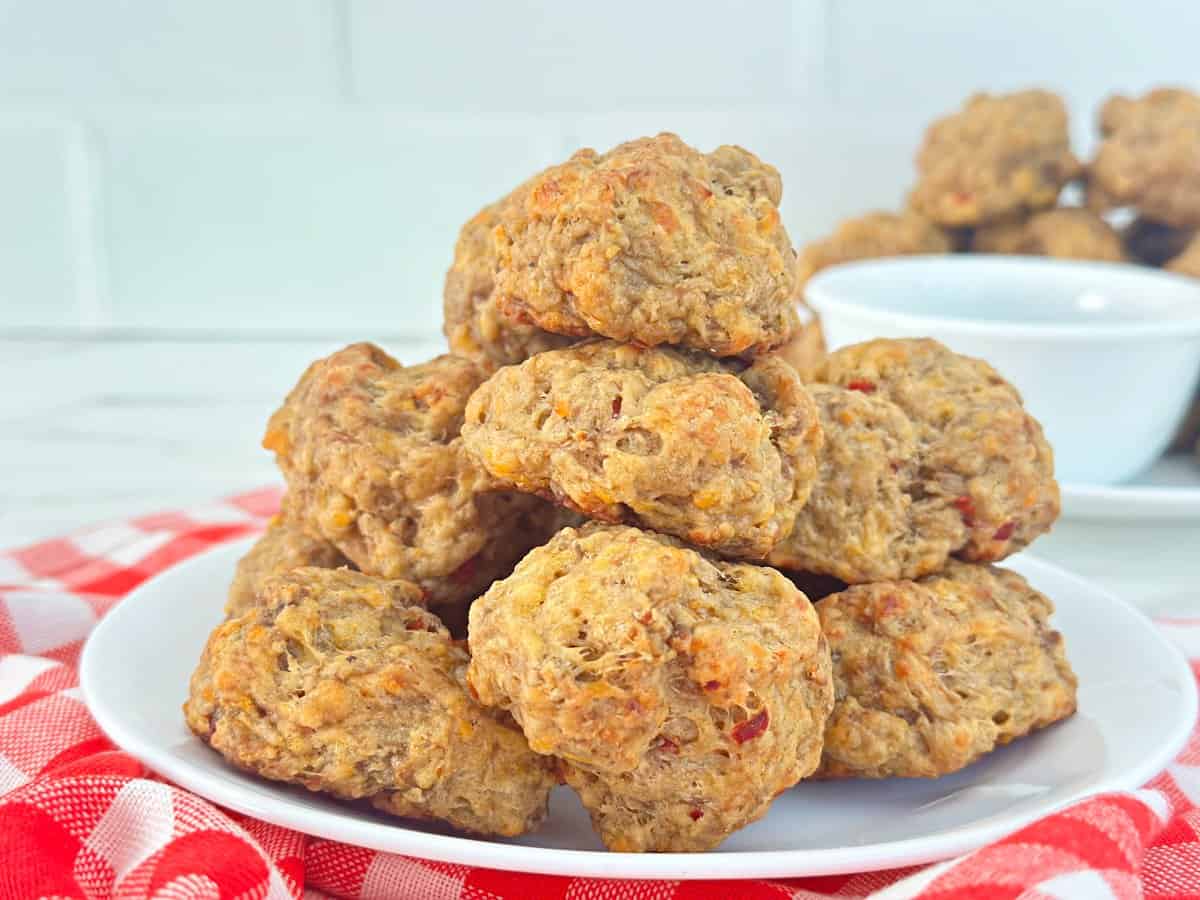 Side view of pimento cheese balls appetizer stacked on white plate.