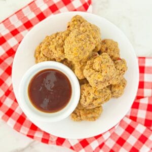 Down view of pimento cheese balls with bisquick stacked next to a bowl with dipping sauce.