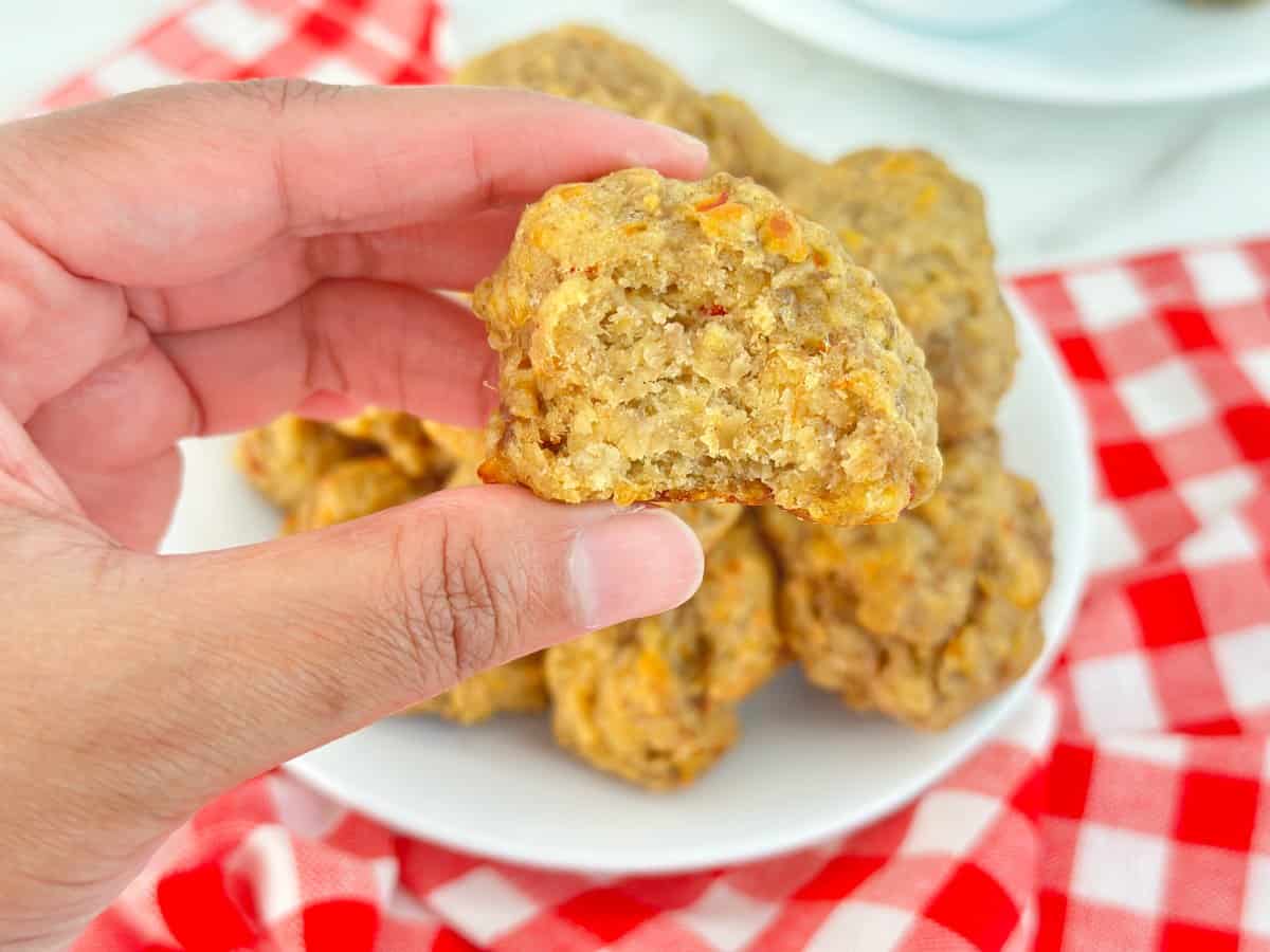 Hand holding a bitten pimento cheese ball to show moist texture.