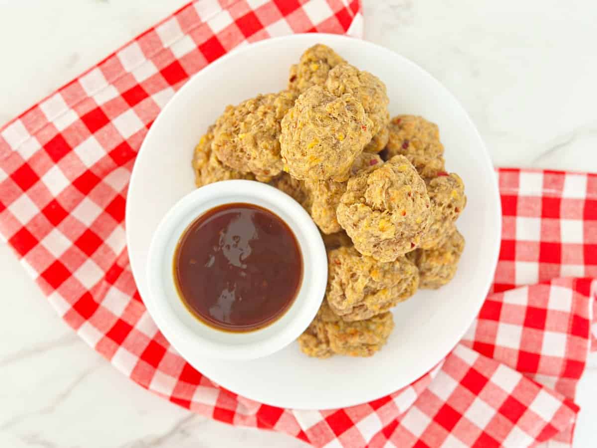 Down view of pimento cheese balls stacked next to a bowl with dipping sauce.